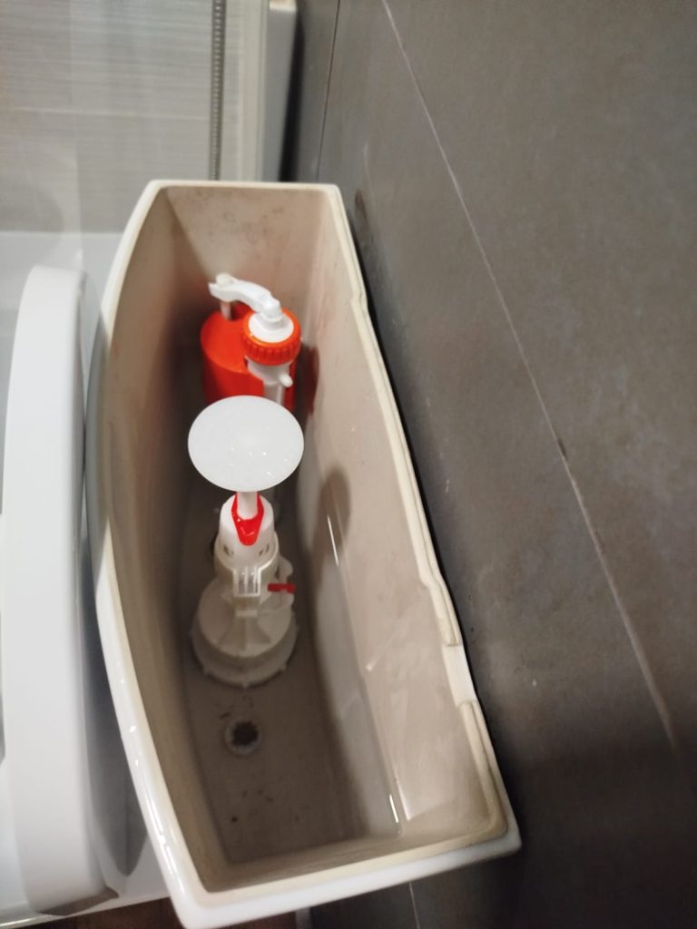 Interior de una cisterna de WC mostrando el mecanismo de descarga y el flotador.

